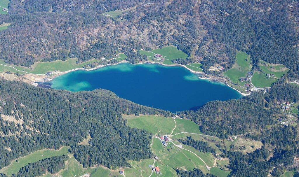 Luftbild des Hintersteiner Sees in Scheffau, umgeben von Wald und Almwiesen